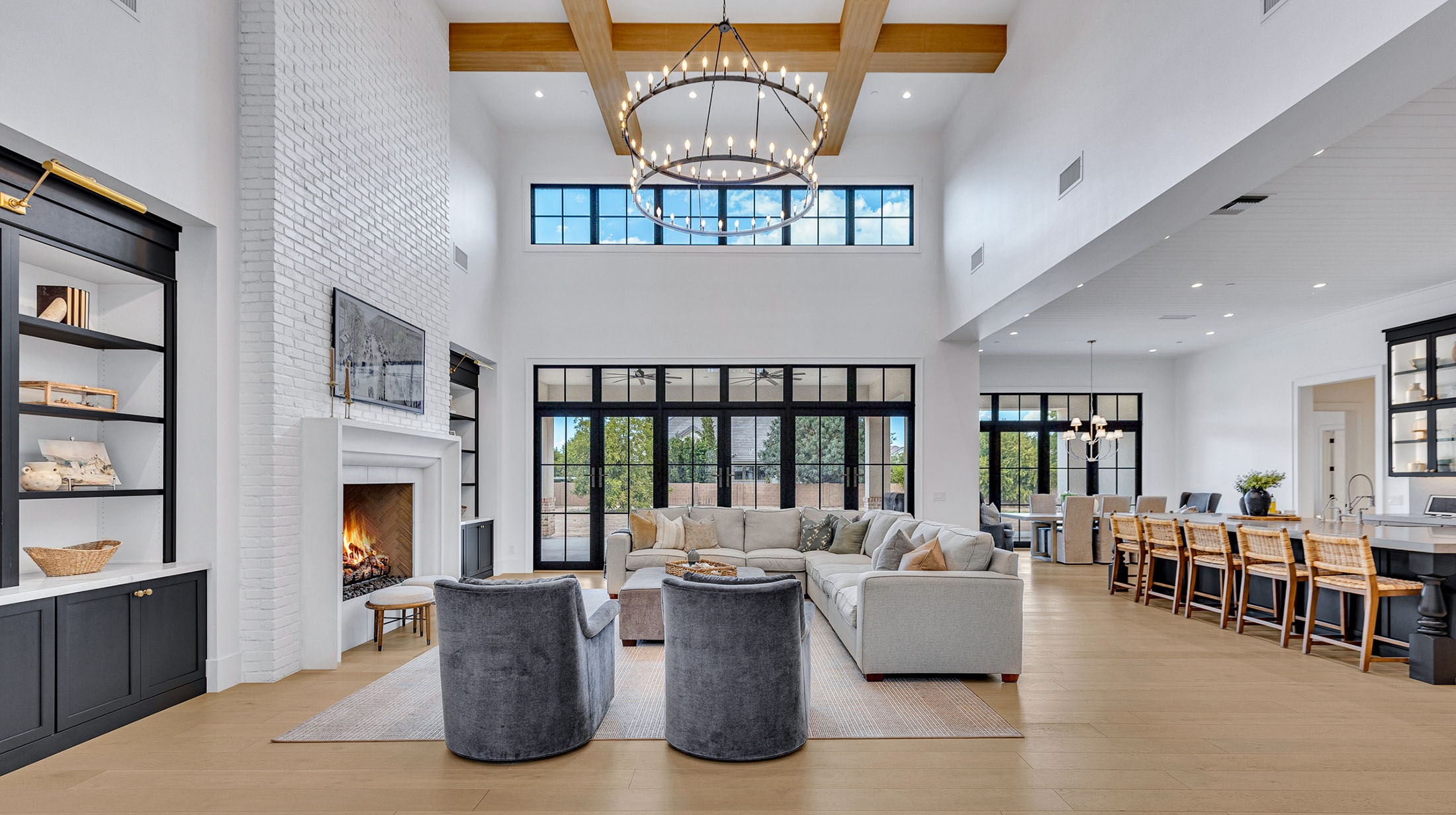 Spacious farmhouse-style kitchen featuring a large island, black pendant lighting, white cabinetry, and an open dining area with industrial accents.