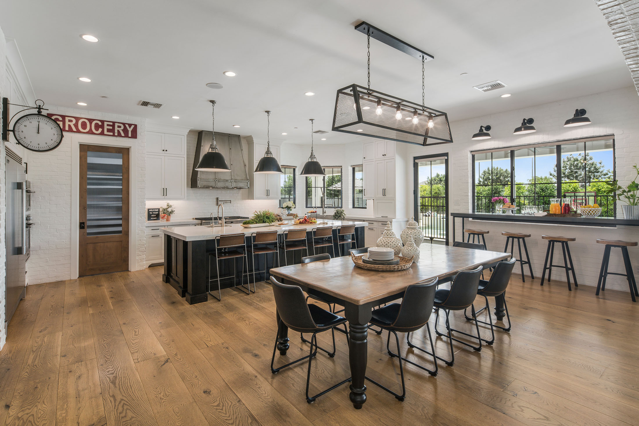 Expansive great room with vaulted ceilings, wood beams, a grand chandelier, and an open-concept layout featuring a cozy fireplace and modern kitchen.