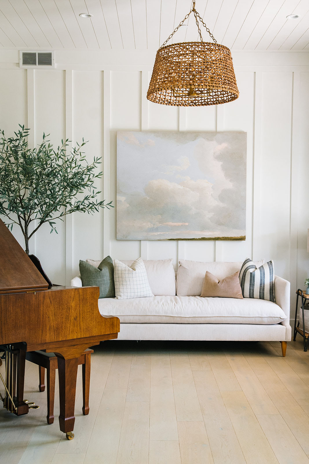 Elegant piano room with a woven chandelier, board and batten walls, and a timeless grand piano.