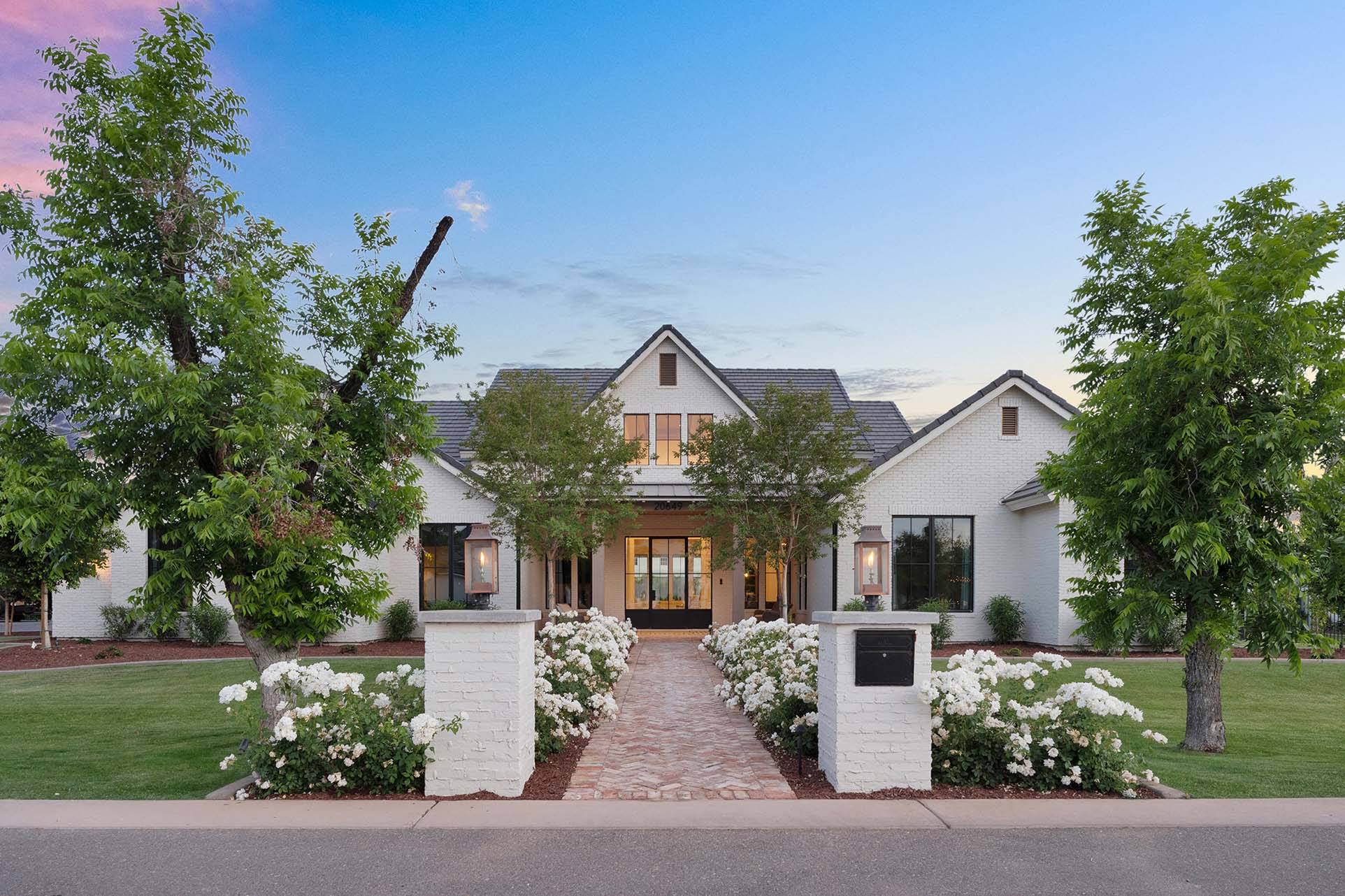 Modern exterior with white brick facade and black-framed windows – A stunning modern home featuring a white brick exterior, black-framed windows, and a welcoming front porch with symmetrical landscaping.